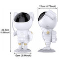 Two astronaut figurines with black visors stand on a gray base, capturing the wonder of the cosmos. One faces forward while the other is in profile. Dimensions: height 22.5 cm (8.86 inches), width 10 cm (3.94 inches), depth 12 cm (4.72 inches). A perfect companion for your Astronaut Galaxy Projector setup!