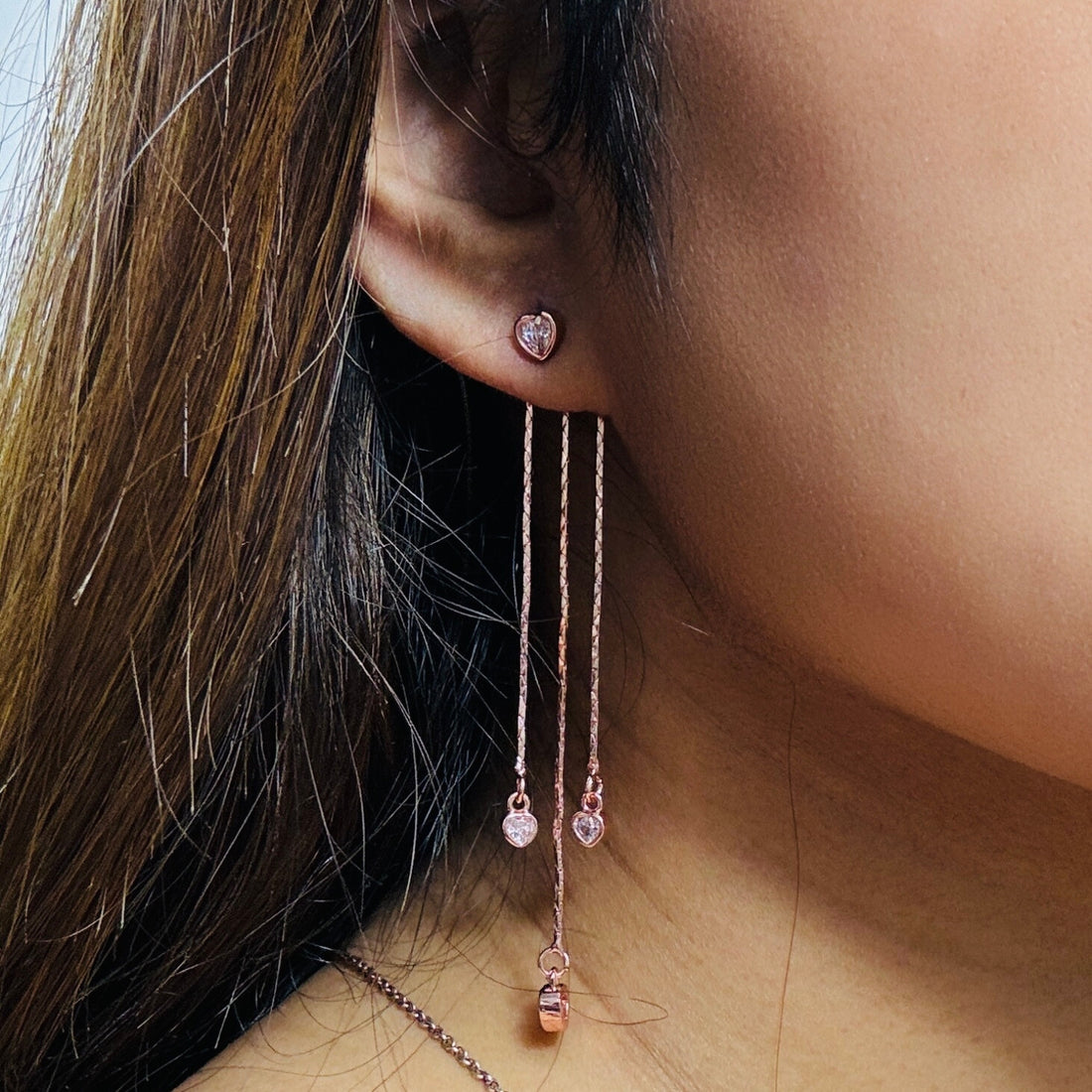 Rosegold heart shaped earrings in a purple background